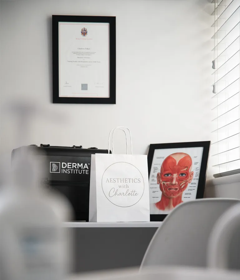 The clinic shelf: Charlotte's framed certificate, a Derma Institute box, her branded bag and a face anatomy chart