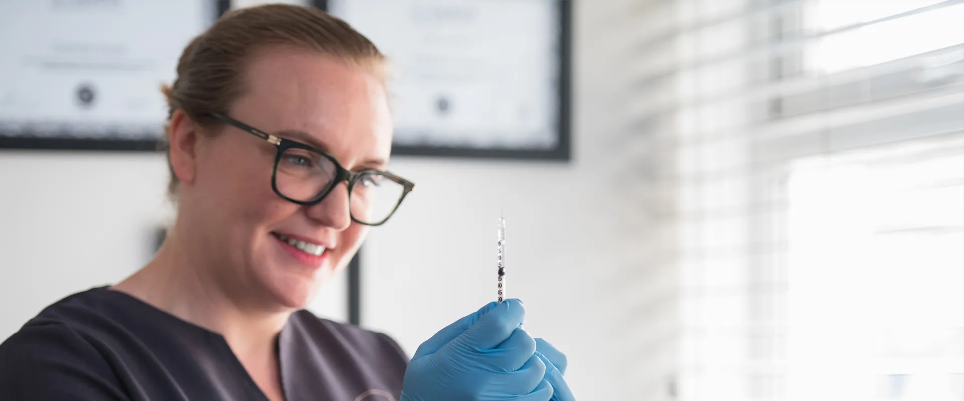 Charlotte, gloved, holding a syringe in her clinic